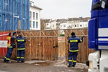 Zur Sicherung des Tors wurde u. A. ein Gitterträger angebracht. Im Hintergrund ist die Baugrube zu sehen.